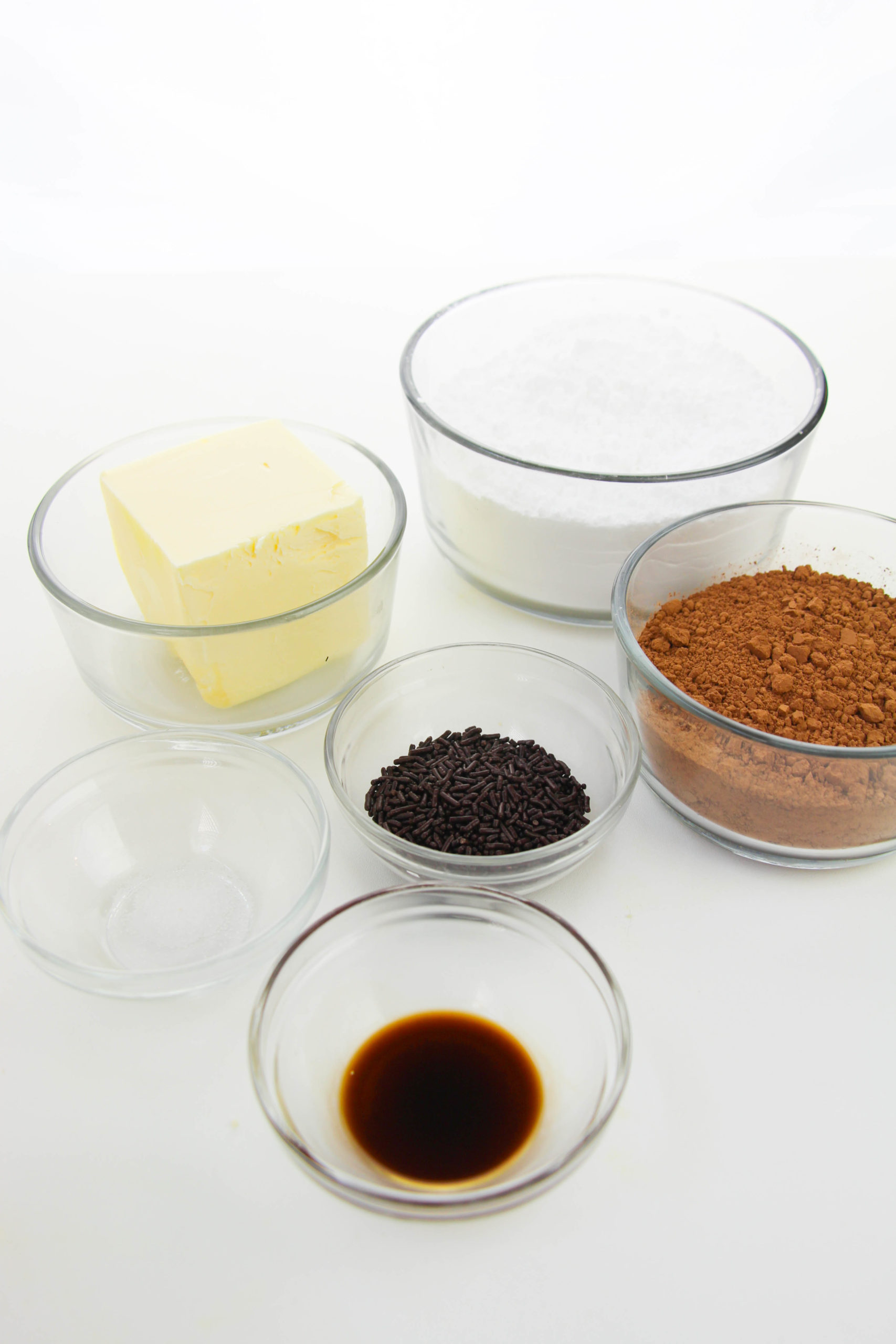 Powered sugar, butter, chocolate and vanilla in clear dishes,