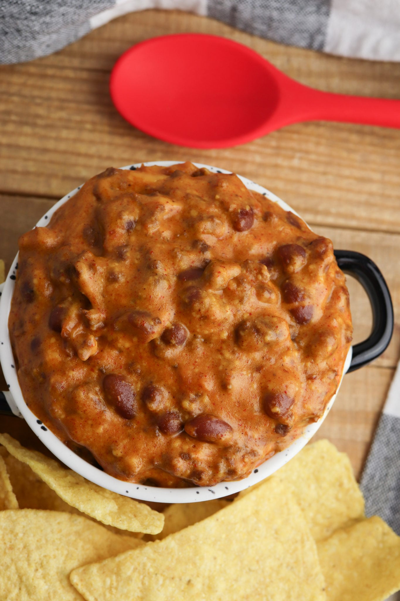 Pot full of the chili with a red spoon on the side.