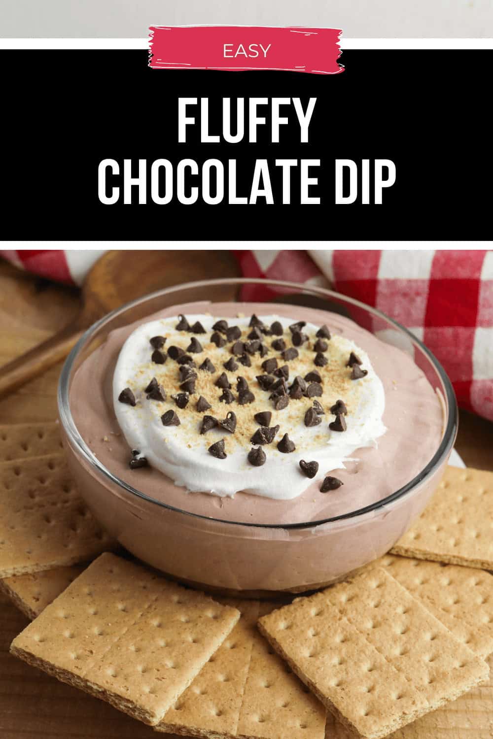 A bowl of fluffy chocolate dip crowned with whipped cream and decadent chocolate chips, all nestled on a wooden surface, with crunchy graham crackers invitingly arrayed around it.