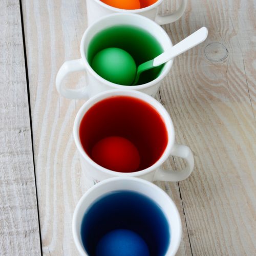 4 cups filled with colored liquid and an egg.