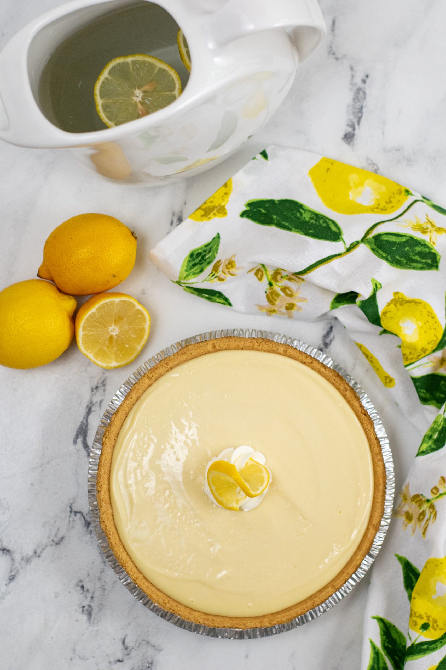 A whole pie uncut with lemons on the side.