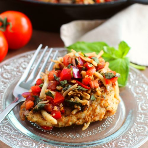 Baked Bruschetta Chicken on a clear dish with a fork.