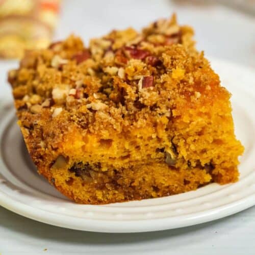 A slice of crumb-topped butterscotch cake featuring a golden, moist texture with visible pecans and streusel, reminiscent of the rich flavors found in butterscotch cake.