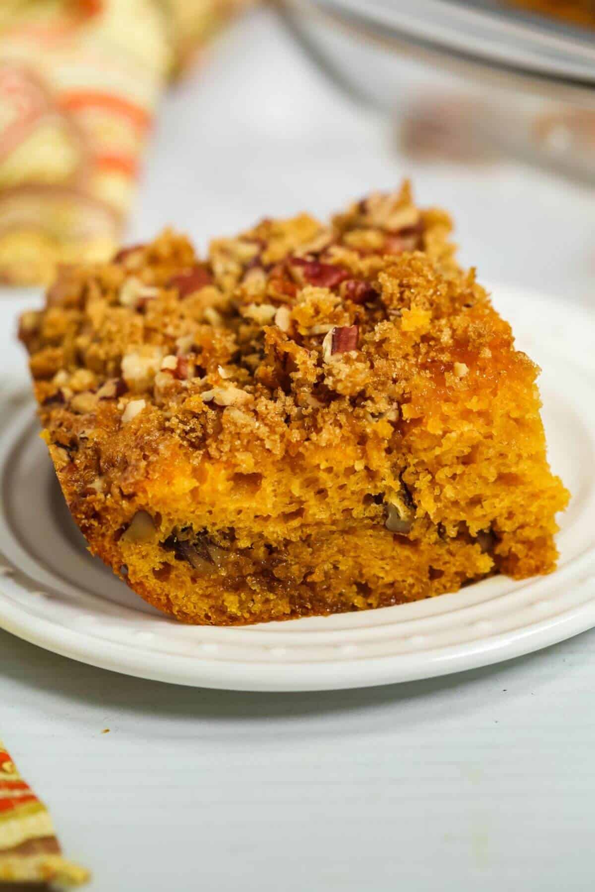 A slice of crumb-topped butterscotch cake featuring a golden, moist texture with visible pecans and streusel, reminiscent of the rich flavors found in butterscotch cake.