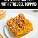 A slice of butterscotch cake with a streusel topping sits on a white plate, garnished with nuts. A colorful napkin lies beside the tempting dessert.