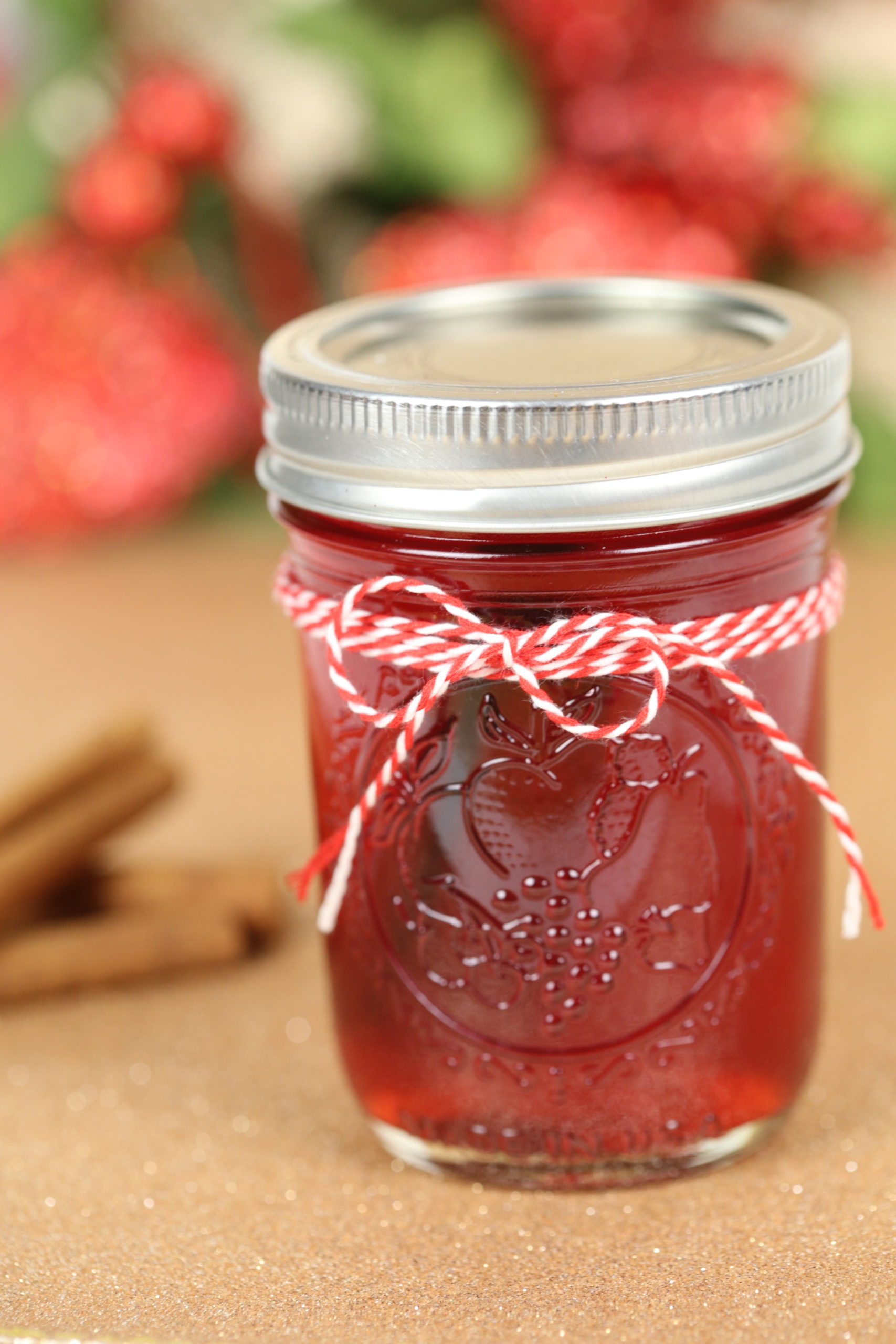 A mason jar filled with cranberry moonshine and decorated with twine.