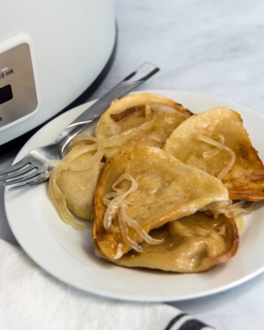 Crock Pot Pierogi on a white plate with a slow cooker in the background