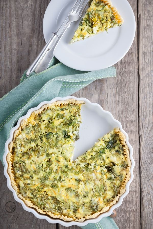  Quiche with ham and spinach in a whit pie dish.