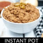 A bowl of instant pot refried beans topped with jalapeño slices, surrounded by ingredients and a checkered napkin.