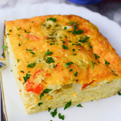 A slice of Mexican breakfast casserole garnished with fresh herbs on a white plate.