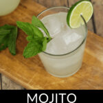 Glass of moonshine mojito with lime and mint garnish on a wooden surface.