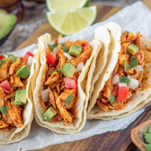 Slow Cooked Shredded Chicken Tacos. three on a white plate.