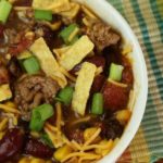 Two bowls of chili with chips on top.