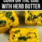 Close-up view of air fryer corn on the cob garnished with herb butter. The crispy, golden corn is topped with mixed green herbs, showcasing a deliciously fresh appearance.