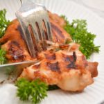 Asian Grilled Chicken being cut by a fork and knife.