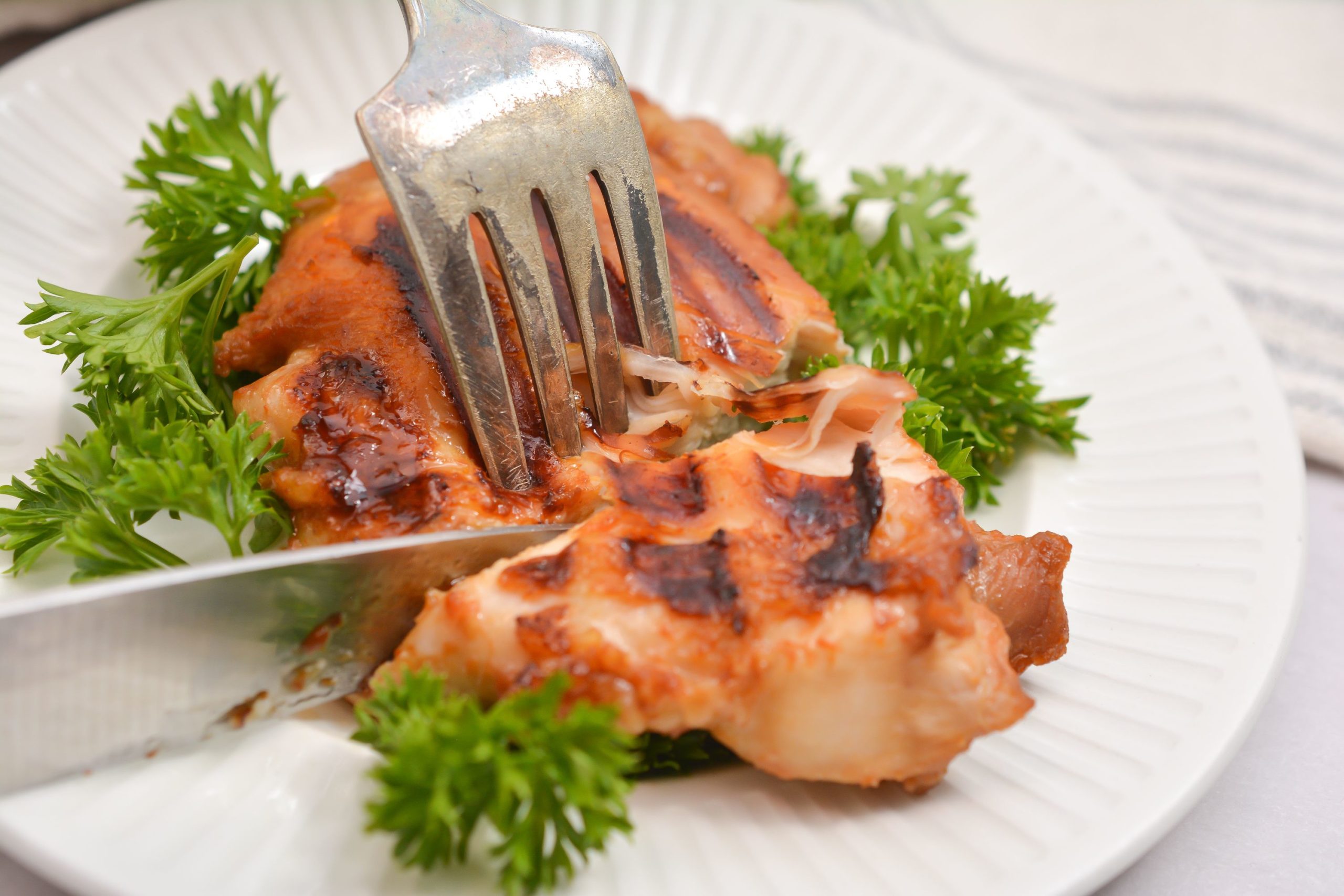 Asian Grilled Chicken being cut by a fork and knife.