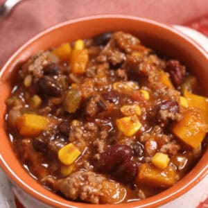 A bowl filled with chunky beef and bean chili containing corn, ground meat, and vegetables.