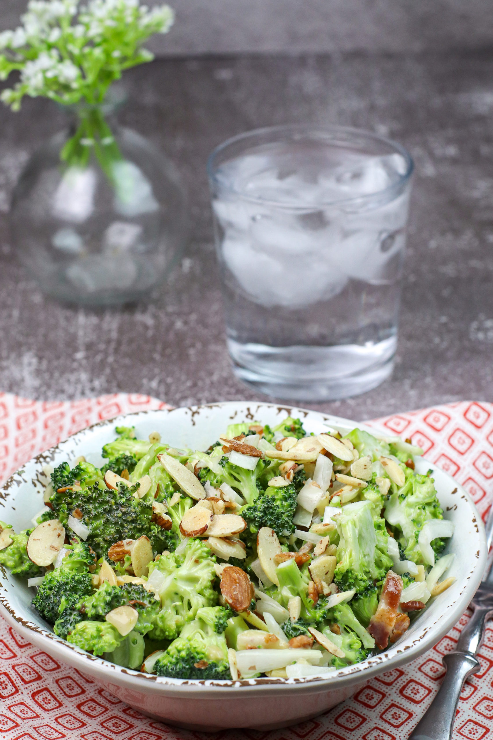 Bowl of broccoli almond salad. A glass of water.