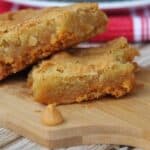 Gooey butterscotch blondies on a wooden cutting board.