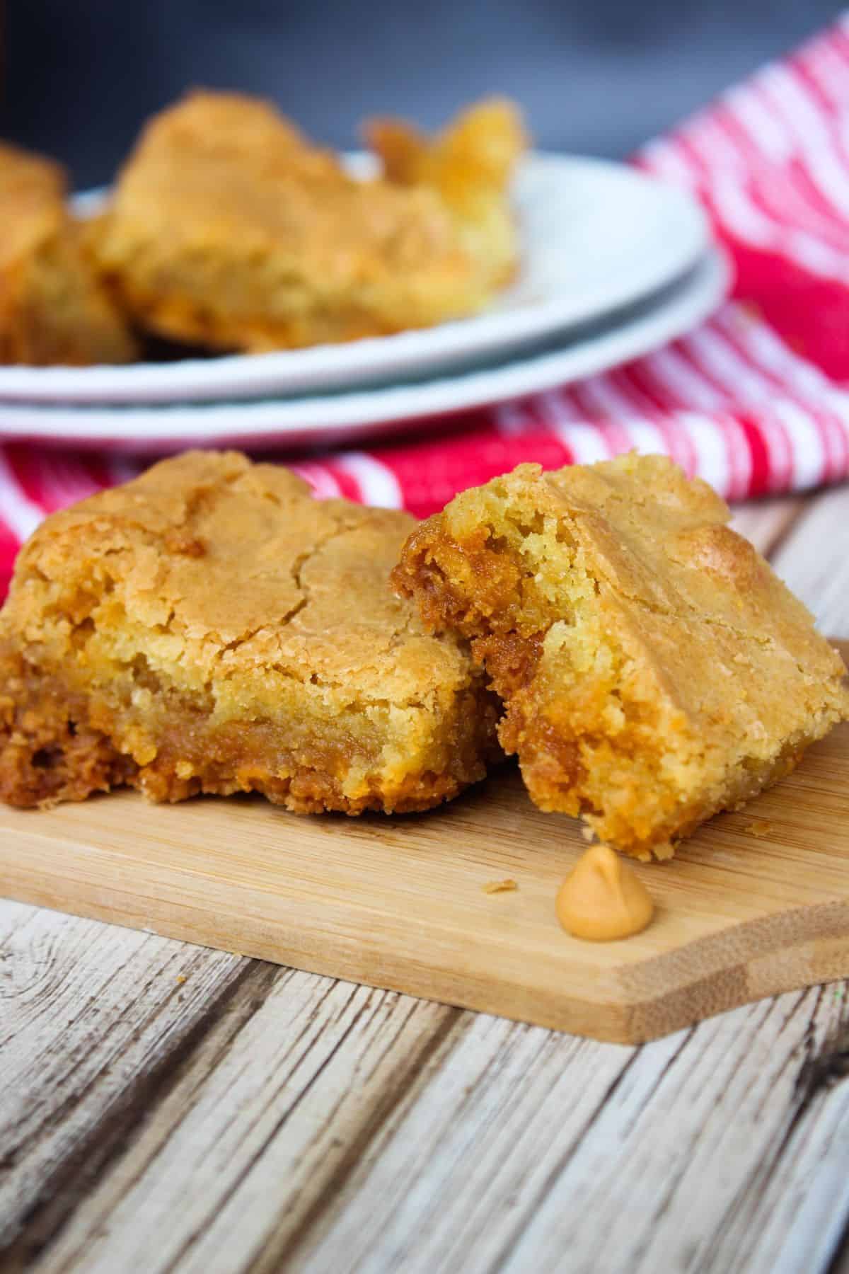 A tray of the butterscotch blondies with a wooden cutting board in front.