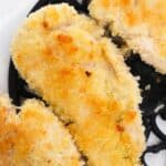Chicken Milanese: Breaded and baked chicken breasts with a golden, crispy coating on a black decorative trivet.
