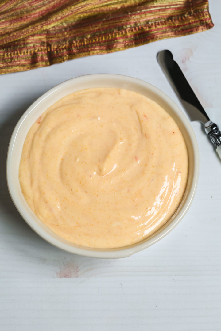 Creamy Sriracha Sauce in a bowl with a small knife