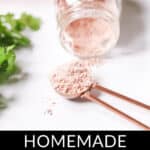 A bottle of homemade fajitas seasoning tipped over, spilling fajitas seasoning onto a spoon, with fresh parsley in the background. Text overlay reads "homemade fajitas seasoning".