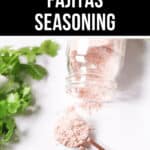 A glass jar with homemade fajitas seasoning spilled onto a spoon, with fresh cilantro visible, and a "homemade fajitas seasoning" label at the top.