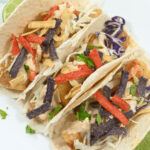 Baja fish tacos with cabbage slaw and chipotle sauce garnished with tortilla strips and cilantro.
