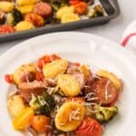 A plate of the main with a baking tray of the same vibrant dish in the background.