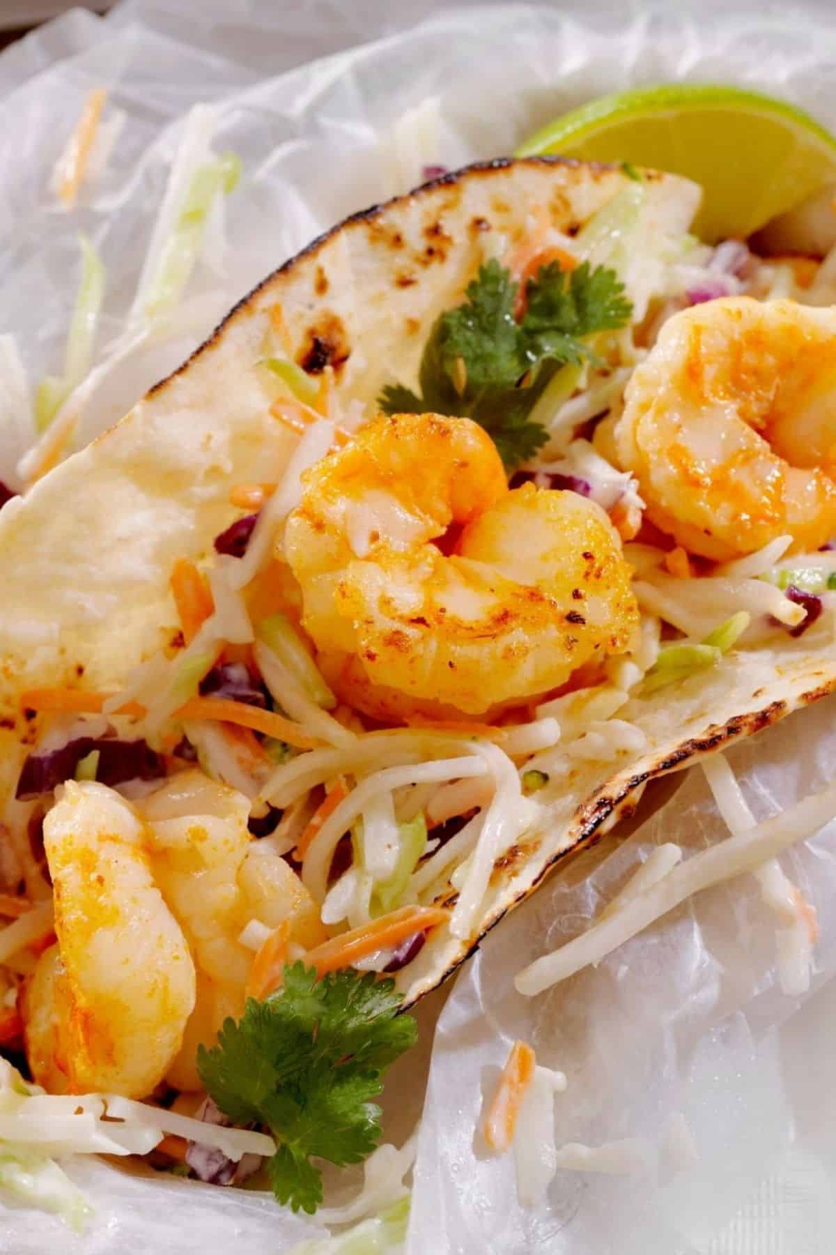 A soft tortilla taco filled with grilled shrimp, shredded cabbage slaw, fresh cilantro, and a tangy mango salsa. Enjoy these Shrimp Tacos with Mango Salsa served with a lime wedge on the side.