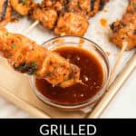 Grilled chicken on a stick being dipped into a bowl of sauce, with more skewers on a tray in the background. Text reads: "Grilled Sticky Chicken on a Stick.