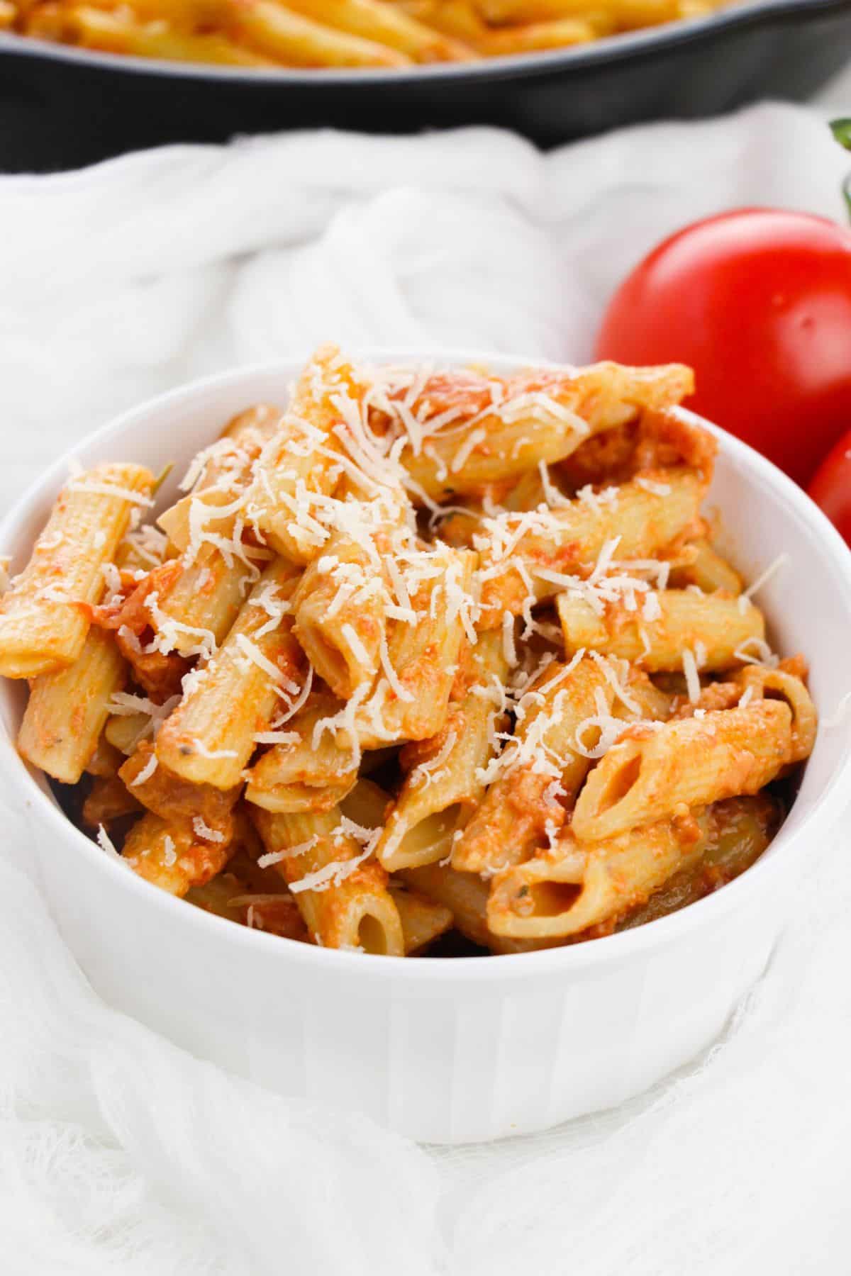 A bowl of pasta topped with cheese and rich tomato, tossed in a creamy vodka cream sauce.