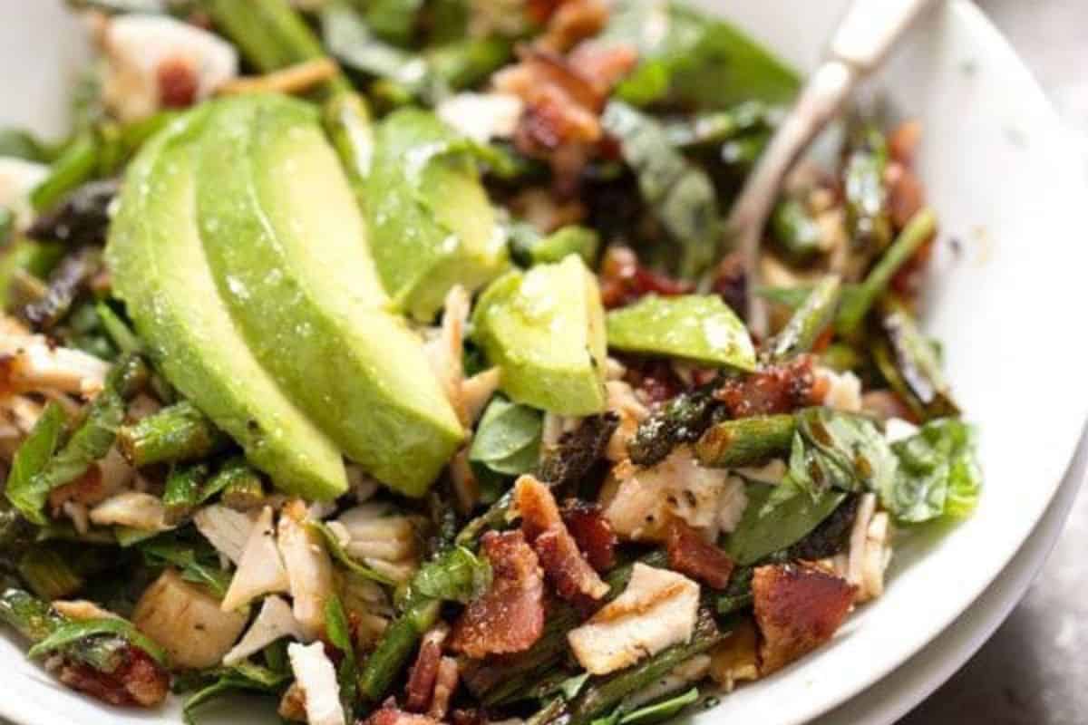 Fresh salad featuring grilled chicken, crispy bacon, creamy avocado, and tender asparagus.