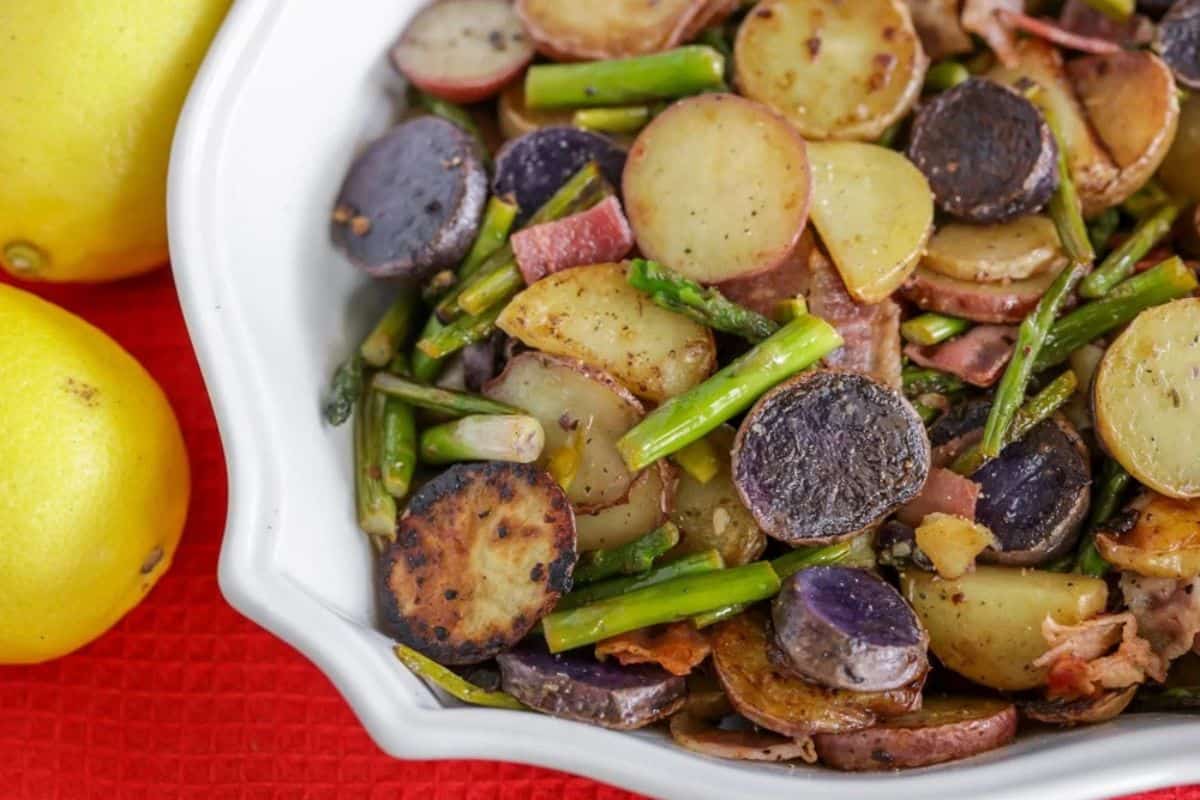 Roasted asparagus and baby potatoes medley on a baking sheet, seasoned with herbs and garlic, featuring a golden, crispy finish.