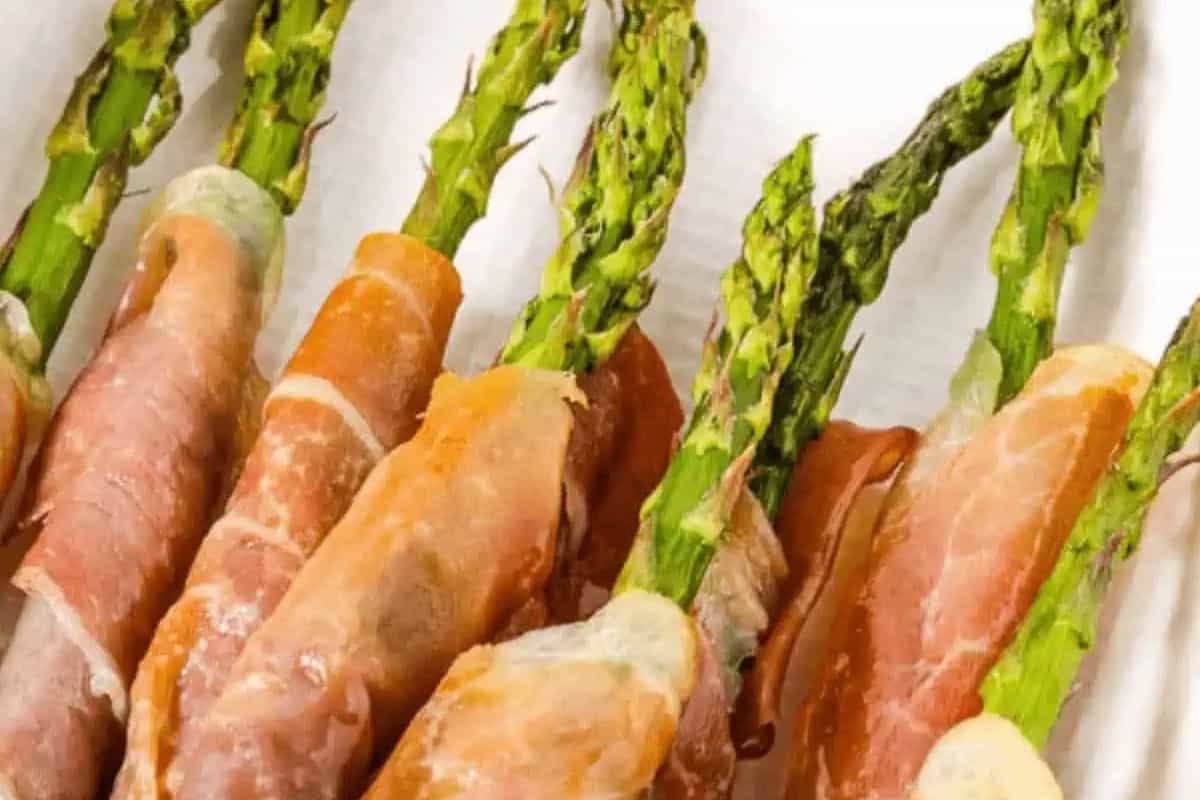 Close up of crispy prosciutto-wrapped asparagus spears arranged on a serving platter.