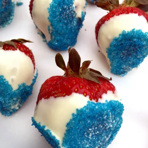 Strawberries covered in white chocolate with blue sugar sprinkles