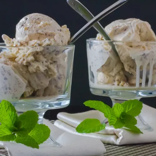 Two glass bowls filled with irish cream ice cream garnished with mint leaves