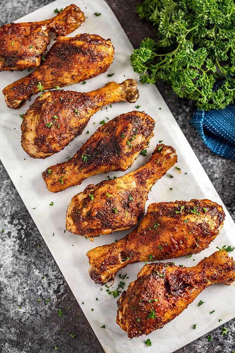 A plate of perfectly cooked grilled chicken drumsticks garnished with parsley