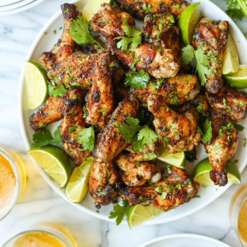 A big pile of cilantro lime baked chicken wings garnished with fresh cilantro and lime