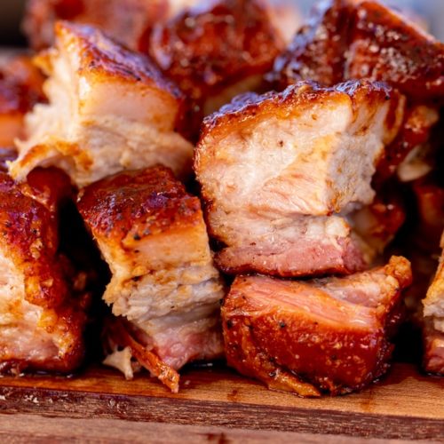 Cubed smoked pork belly stacked on a wooden platter