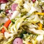 A close-up of Fried Cabbage and Sausage, with sliced sausage and bell peppers mixed together in a pan.