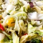 Close-up of Fried Cabbage and Sausage mixed with sliced sausage and pieces of red and yellow bell peppers.