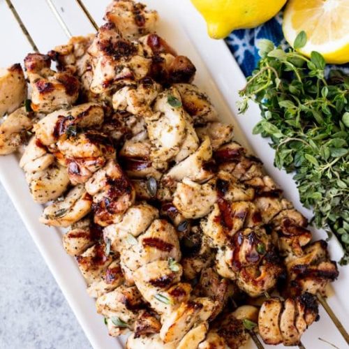 A plate stacked with grilled chicken skewers with lemon herb seasoning