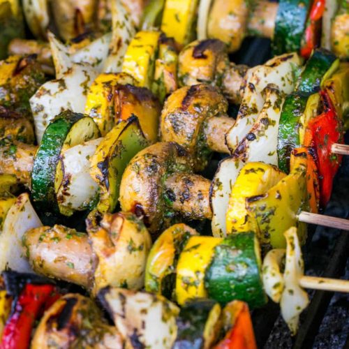 Vegetable skewers on a grill with cucumber, bell peppers, onions, and mushrooms