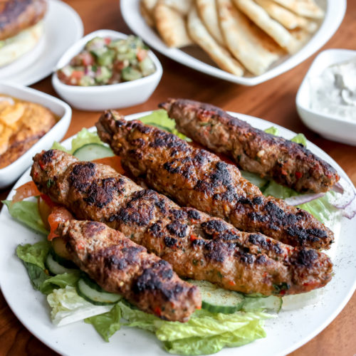 ground lamb kabobs scaled on a plate with side dishes