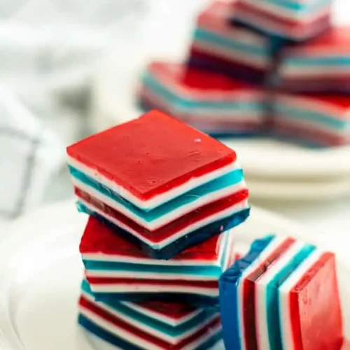 Layered jello squares stacked on a white plate.