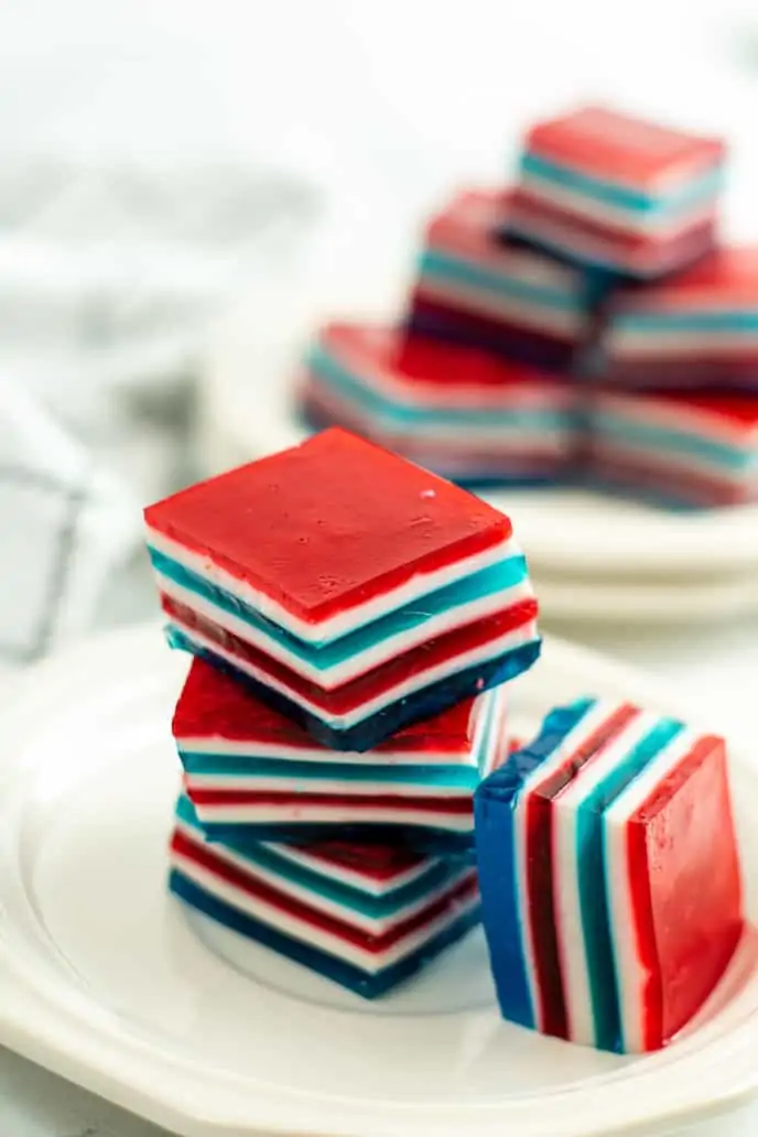 Layered jello squares stacked on a white plate. 