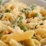 A close-up of a bowl of Lemon Asparagus Pasta, featuring penne mixed with asparagus and topped with grated cheese.