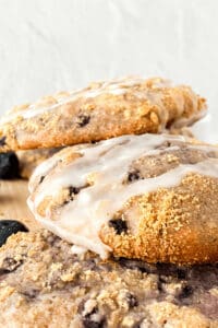 Close-up of three freshly baked dessert drizzled with icing, stacked on a wooden surface.